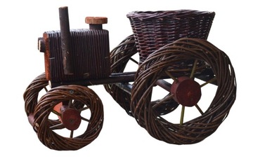 Wicker tractor dark flowerbed on flowers garden, фото
